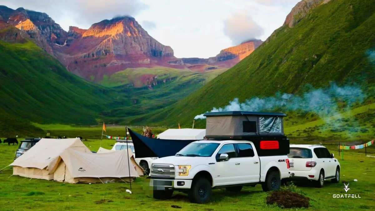 demountable camper truck in a green field with mountains in the background