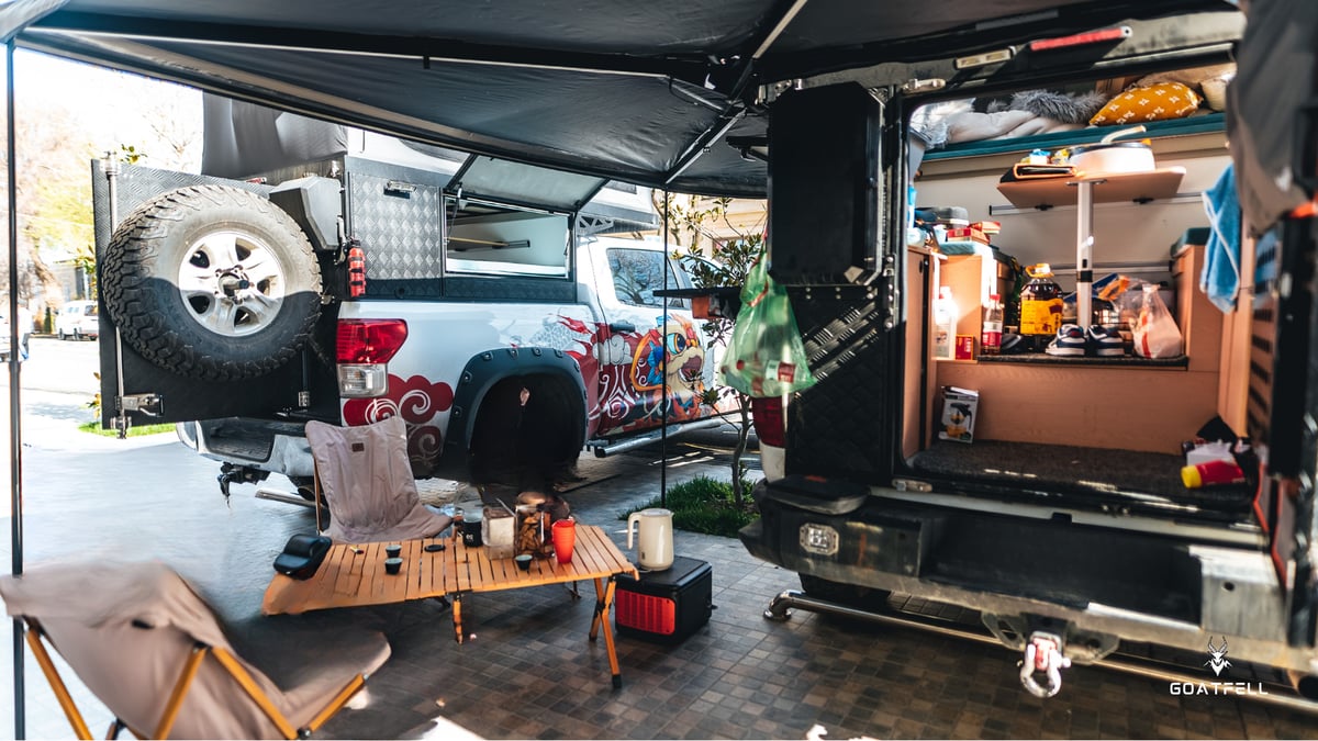 rear of demountable camper truck with awning and table and chairs